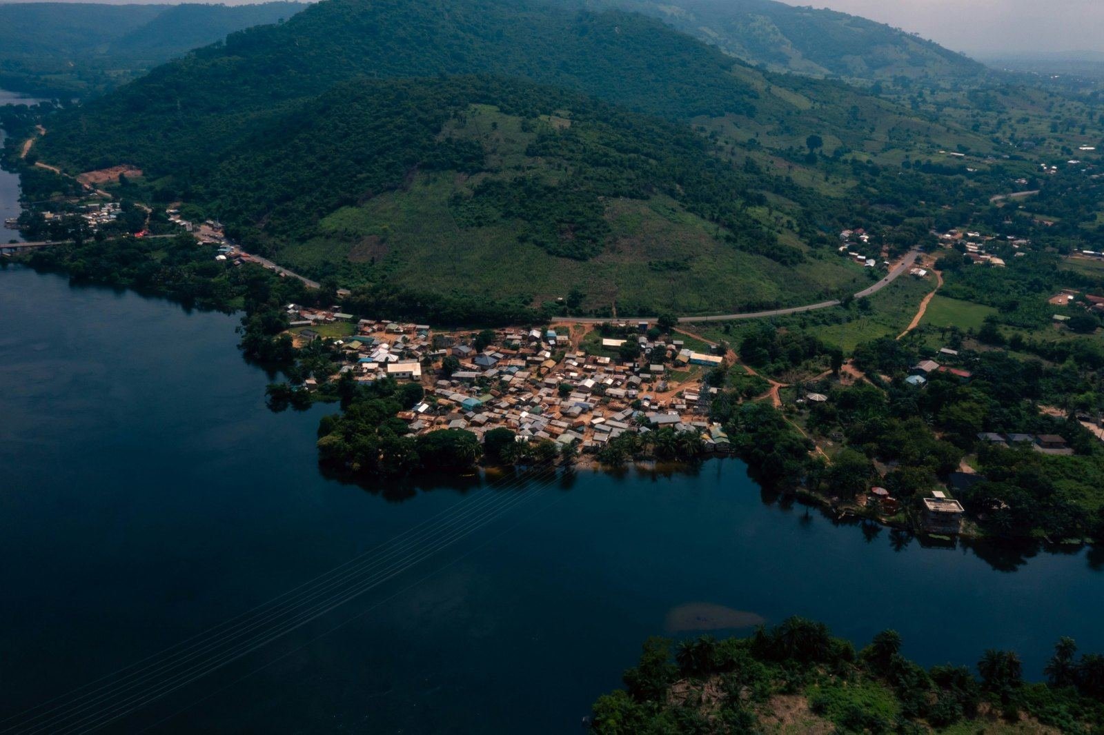 Aerial view of a lakeside settlement beneath forested hills.